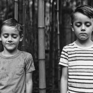 Two brothers stand next to each other in bamboo