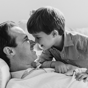 Son sits on top of Dad while giving nose kisses