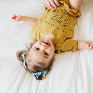 Little girl laughs while laying on bed