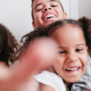 3 sibling laugh and reach toward camera