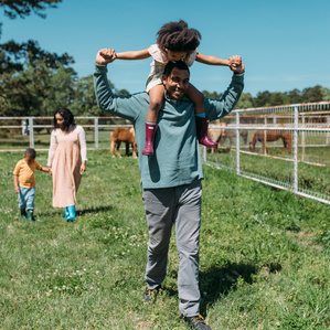 Family of 4 walks around farm property on sunny day outside