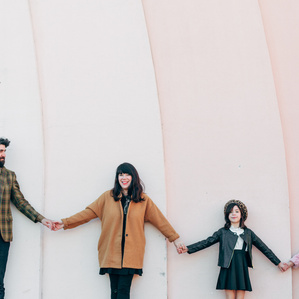 Family of 4 standing by a colorful wall