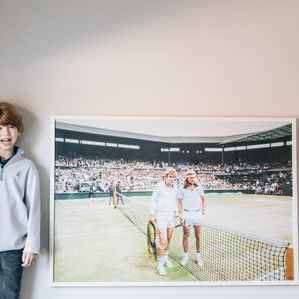 Boy stands next to framed artwork