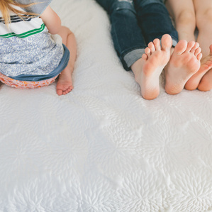 Mothers feet with daughters on bed