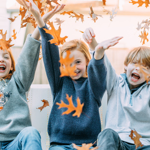 3 siblings toss leaves into the air
