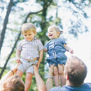 Twin kids held up by Dads in park