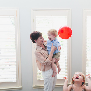 Mom holds son while daughter tosses balloon