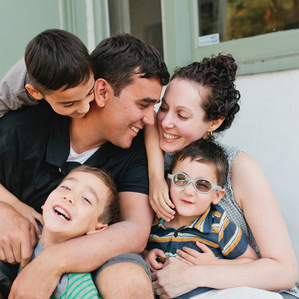 Family of 5 sits together on front porch smiling