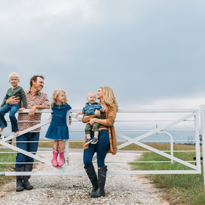 Family stands at gate to property in country