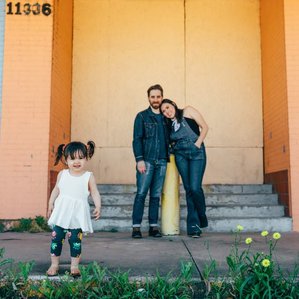 Parents look at daughter next to colorful old building