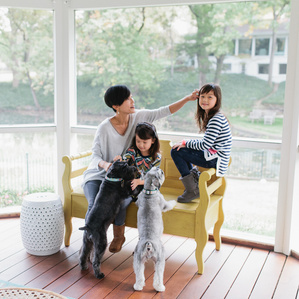 Mother sits with daughters and dogs on patio