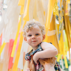 Boy is held up by Father next to colorful streamers