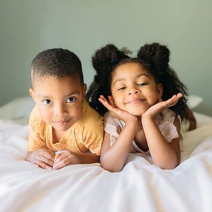 Brother and sister together on bed being silly