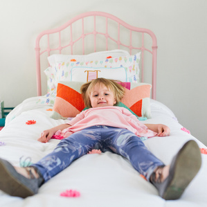 Girl sits on bed with legs stretched out