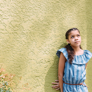 Young girl daydreaming next to colorful wall