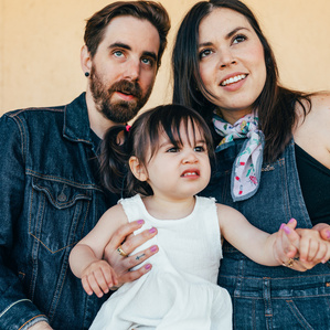 Mother and father stand with toddler daughter looking into distance