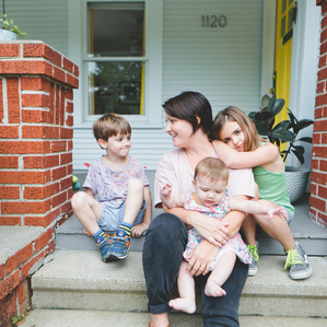 Mother sits on front porch steps with kids