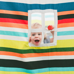Little girl plays peekaboo in playhouse window