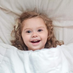 Little girl laughs under covers