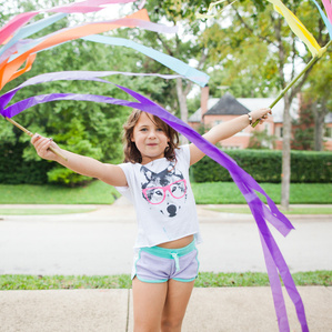 Girl plays with colorful streamers at park