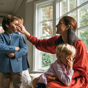 Mom fixes sons hair next to window in living room