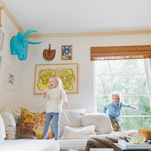 Kids jump together on couch in living room
