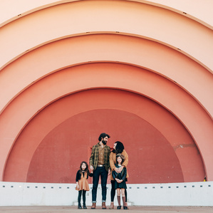 Family of 4 stands in front of rainbow backdrop together