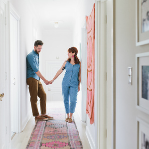 Couple stands holding hand in hallway of home
