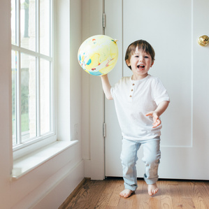 Little boy throws balloon and smiles in home