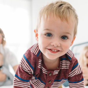 Middle child moves toward camera with family smiling in background