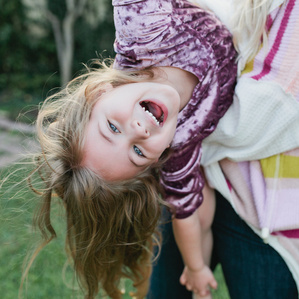 Girl hangs upside down in moms arms being silly