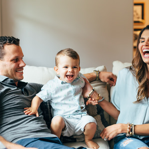 Mother and Father laugh along with son on couch