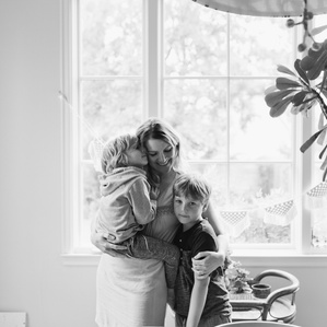Mother embraces sons next to window