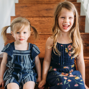 Two sisters sit together on stairs
