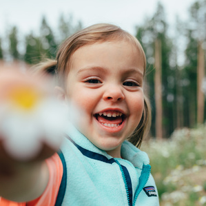Girl holds flower up to camera