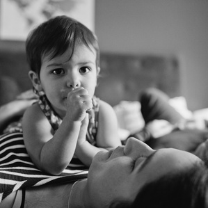 Girl with thumb in her mouth lays on mom's chest