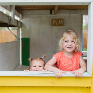 Girls peek out from yellow playroom window