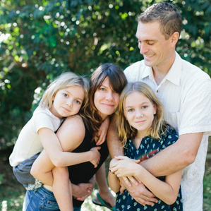 Family stands together smiling in backyard