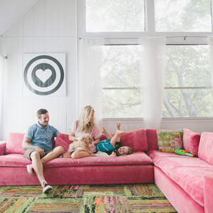 Father, Mother and son play around on big pink couch together