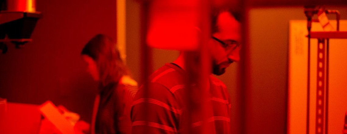 Two people in a dark room examining photos