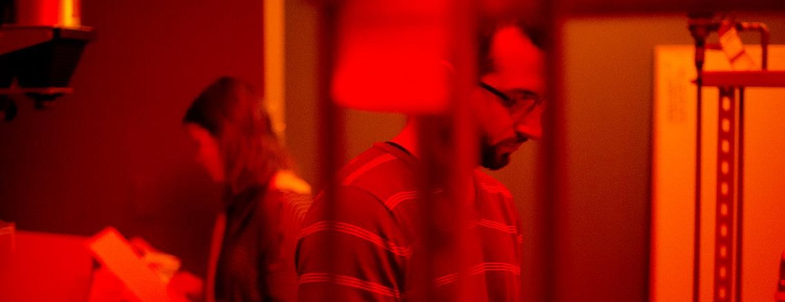 Two people in a dark room examining photos