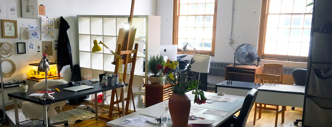 An artist workspace with desks and an easel