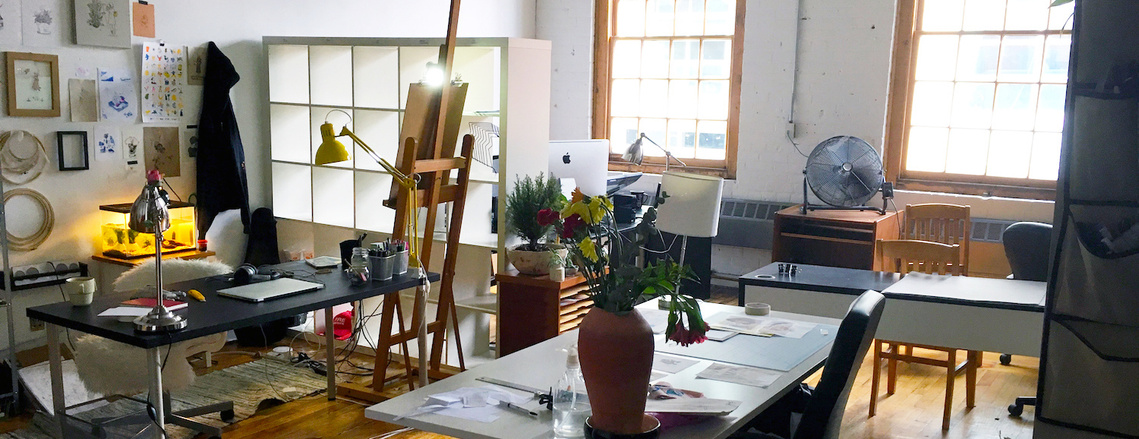 A studio with desks, easels, and various art pinned to the wall