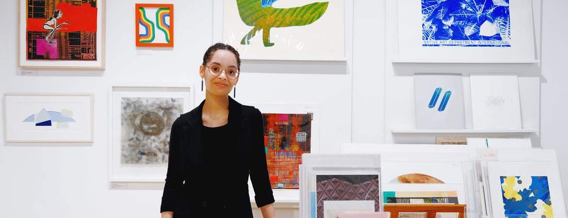 Erica Jochim standing inside a studio, surrounded by paintings
