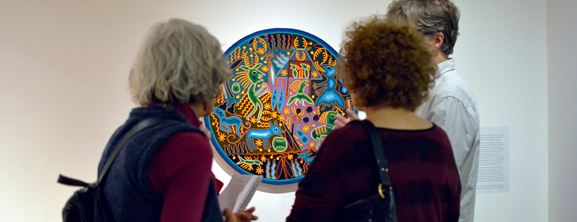 Three people observing a piece of art