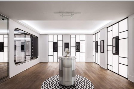 backlit white walls with watch displays surrounding the sculpture of a watch mechanism.