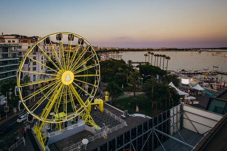 yellow ferris wheel set on the Cannes boardwalk at sunset