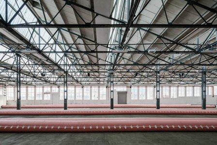 rows of pink flood barriers inside am empty warehouse