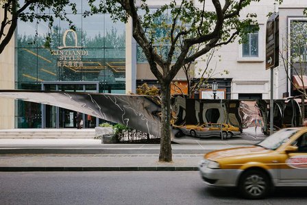 yellow taxi reflecting on a mirror sculpture in an empty shanghai street