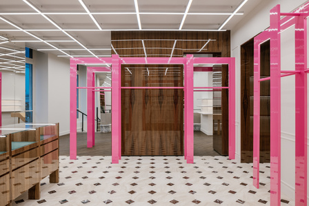 Glossy metallic structures set in a room lit by a white neon grid with lacquered wooden furniture.